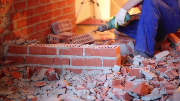 Mãos segurando perfurador quebrando parede de tijolo vermelho no novo apartamento — Vídeo de Stock