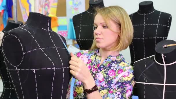 Tailor stands among mannequins and measures size of figure — Stock Video