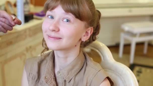 Ruce maskérka aplikovat make-up na usmívající se krásnou dívku — Stock video