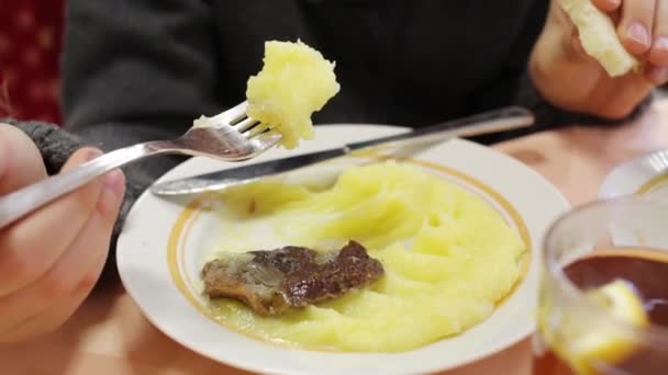 Ruce chlapce jíst maso a bramborovou kaší s nožem a vidličkou — Stock video