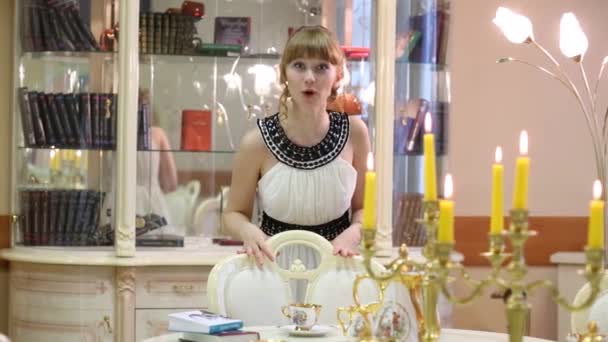 Девушка склоняется возле стеклянного шкафа и стола со свечами — стоковое видео