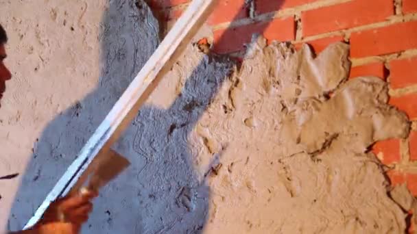 Працівник робить штукатурну стіну за рівнем інструменту і розчину цементу — стокове відео