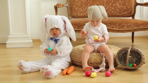 Bebé niño y niña en trajes de conejos sentarse con huevos — Vídeos de Stock