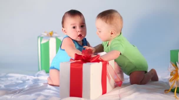 Zwei kleine Babys spielen mit großer Geschenkbox im Atelier — Stockvideo