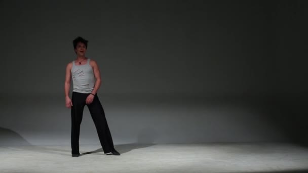 Young brunet dancer in jersey whirls in jump in studio — Stock Video
