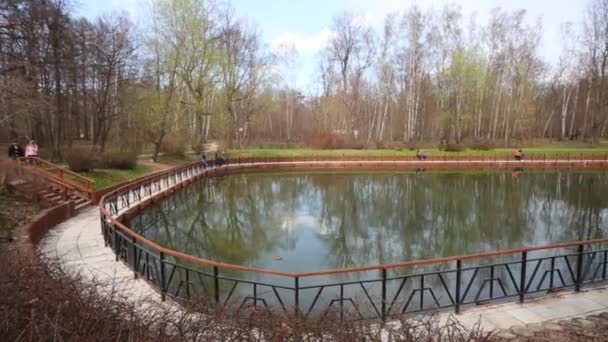 Mensen lopen in de buurt van kleine vijver in Spring Park Sokolniki — Stockvideo