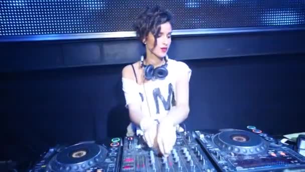 DJ mujer con auriculares baila detrás de la máquina en discoteca — Vídeo de stock