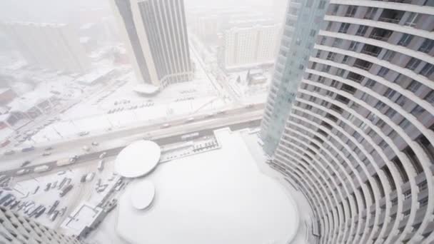 Met het oog op de weg en hoog gebouw tijdens sneeuwval op de winterdag — Stockvideo