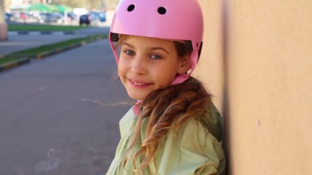 Hermosa chica en el casco rosa sonríe en el día de primavera — Vídeos de Stock