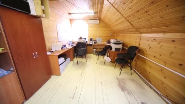 Man is working at a computer in the office with wooden walls — Stock Video