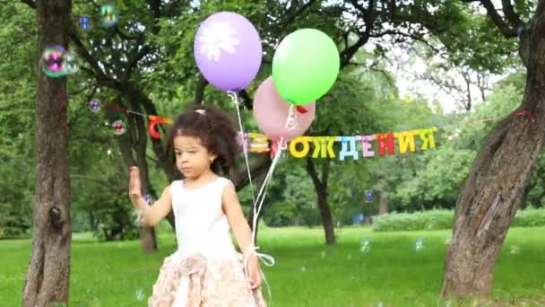 Malá holčička se třemi balónky zachytí mýdlové bubliny — Stock video