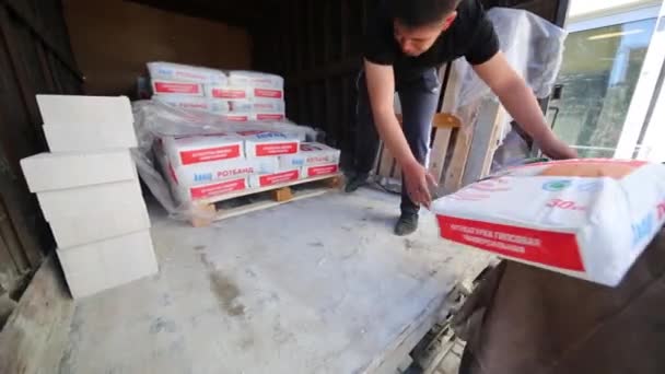 Twee mannen lossen vrachtwagen met zakken van droge mortel Knauf. — Stockvideo