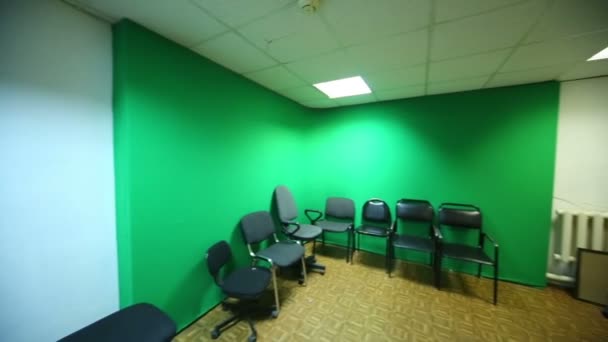 Ontspanningsruimte met groene muur en verschillende stoelen langs het. — Stockvideo