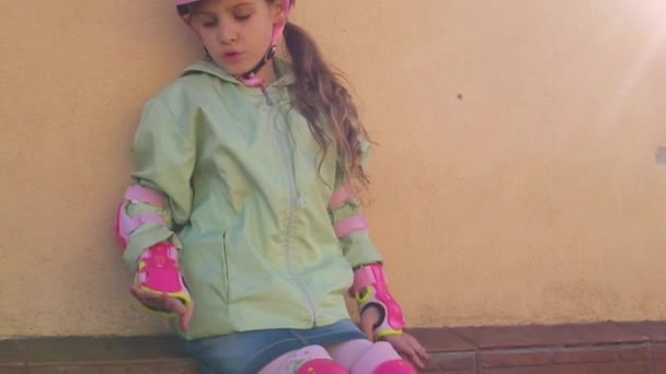 Девушка с роликовыми коньками в розовом шлеме и защита рук — стоковое видео