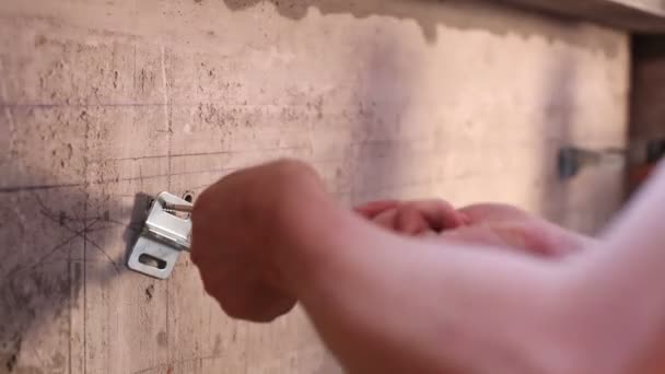 Hands of worker twists screw into dowel mounted in wall. — Stock Video