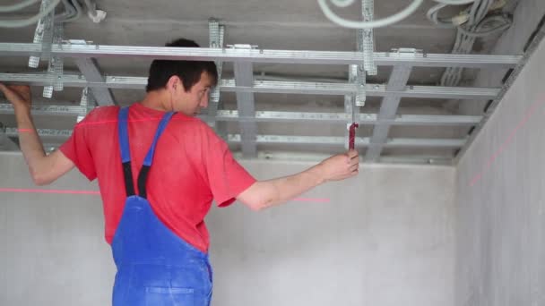Homem verifica a precisão do quadro de instalação para o teto pendurado — Vídeo de Stock