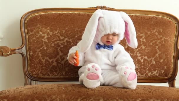 Baby Boy i vit kostym av kanin sitter på Vintage soffa — Stockvideo