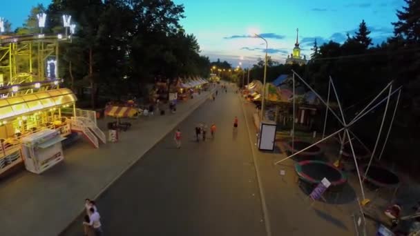 La gente camina por el callejón con tiendas de campaña y diversiones en el parque de VDNH — Vídeo de stock