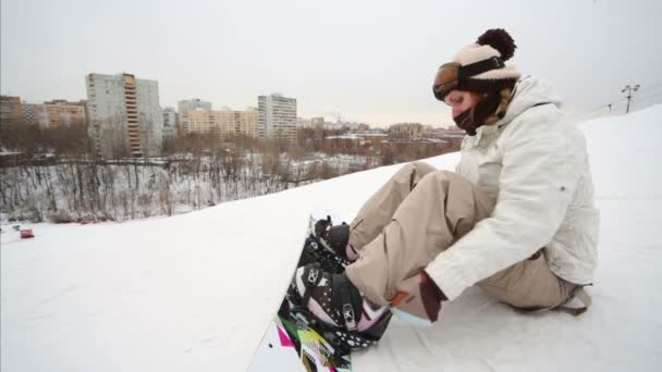 Flicka snowboardåkare sitter på snön och bär solglasögon — Stockvideo