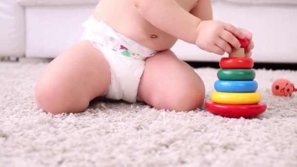 Manos de niño en pañal sentado en la alfombra y jugando con la pirámide — Vídeo de stock