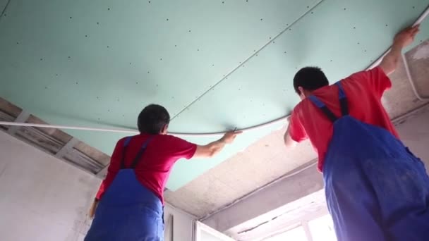 Twee mannen in overalls zijn gemonteerd plafond in nieuw appartement — Stockvideo