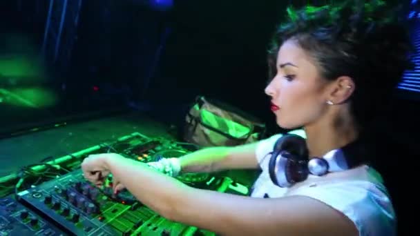 DJ chica con auriculares baila detrás de la máquina en discoteca — Vídeos de Stock