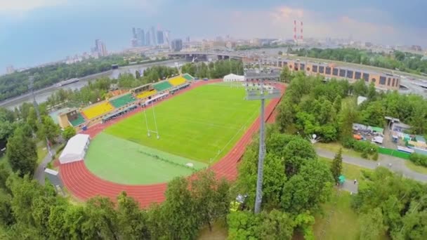 Stade de rugby contre paysage urbain avec circulation sur le pont — Video