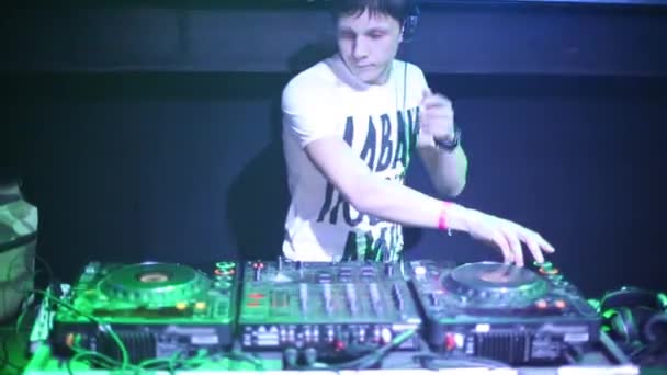 DJ mit Kopfhörern steht hinter Maschine in Nachtclub — Stockvideo