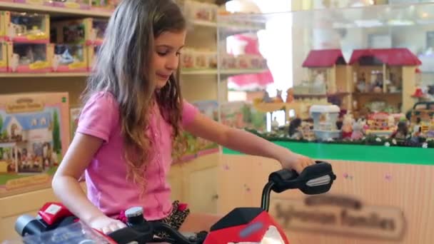Chica se sienta en la motocicleta de juguete en la Galería de Niños Jakimanka . — Vídeos de Stock