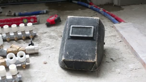 Plumbing vents, level tool, welding mask on the floor — 图库视频影像