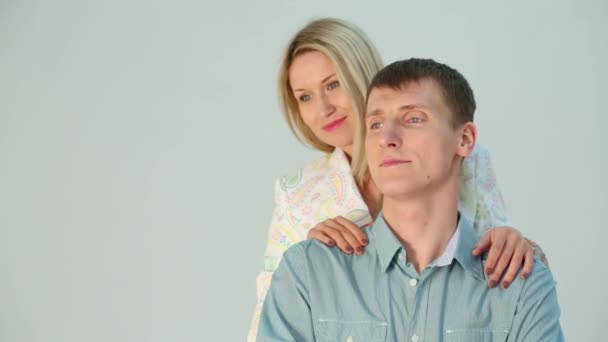 Woman hugging man from behind the shoulders near the gray wall — 图库视频影像