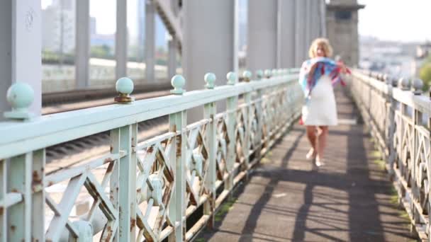 Красивая беременная женщина в белом с шарфом ходит по железнодорожному мосту — стоковое видео
