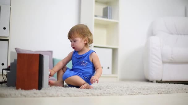Söt unge i blått berör stereosystem på mattan i rummet — Stockvideo