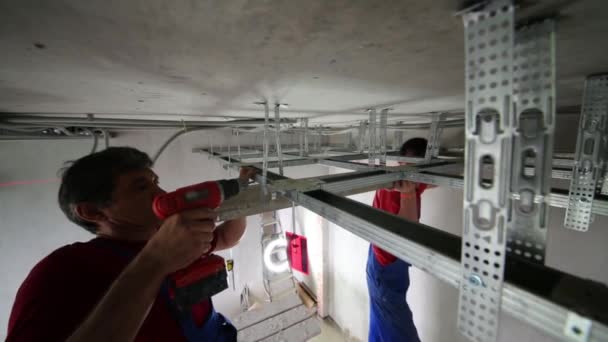 Workers with screwdriver, building level fasten ceiling profile — Stock Video