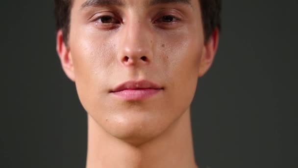 Närbild porträtt av stilig ung man på grå bakgrund — Stockvideo