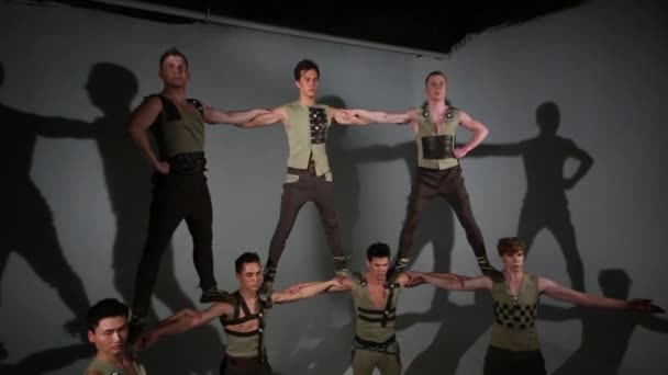 Zeven jongens in middeleeuwse kostuums doen acrobatische piramide in studio — Stockvideo