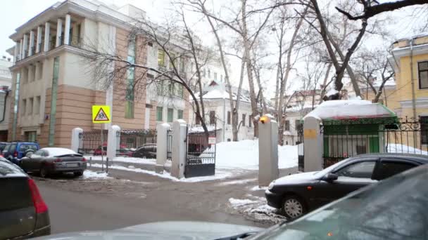 Vuile weg met ontdooide sneeuw, geparkeerde auto's, open poort naar binnenplaats. — Stockvideo
