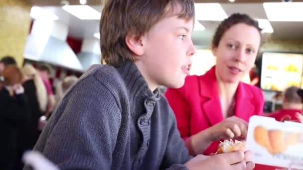 Bonito menino e mãe têm lanche no restaurante fast food — Vídeo de Stock