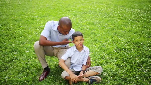 Garçon assis sur l'herbe avec son père — Video