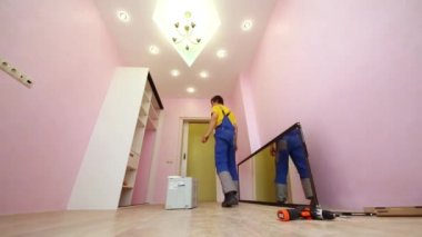 Genç bir işçi sürgülü gardırop görünüyor