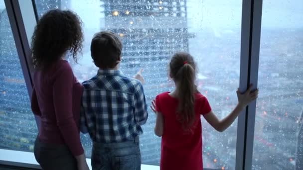 Matka i dzieci patrząc przez okno — Wideo stockowe