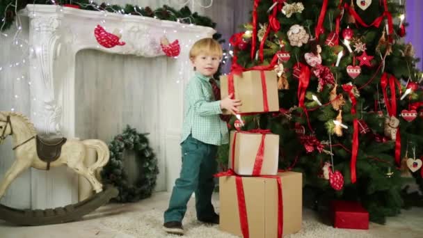 Мальчик играет с подарочными коробками — стоковое видео