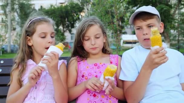 Kleine meisjes en jongen eten maïs. — Stockvideo