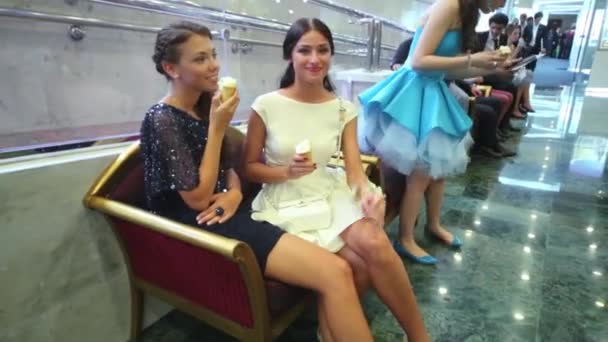 Girls are sitting on bench and eating ice-cream at Graduate-2013. — Stock Video
