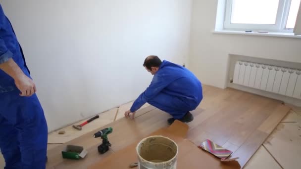 Trabajador pone suelo de madera en el apartamento — Vídeo de stock