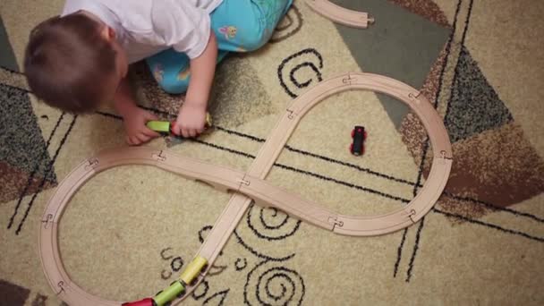 Niño juega con ferrocarril de madera — Vídeos de Stock