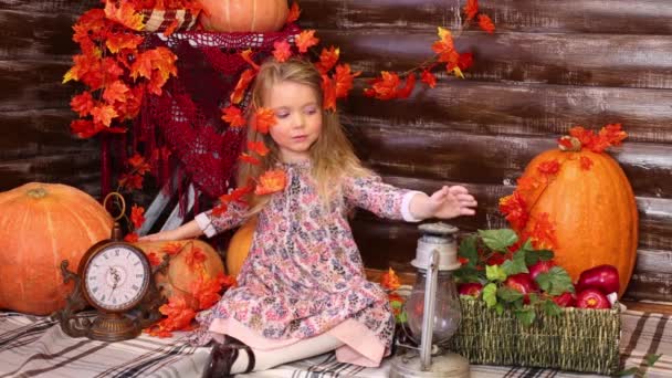 Niña se sienta en la habitación con calabazas — Vídeo de stock