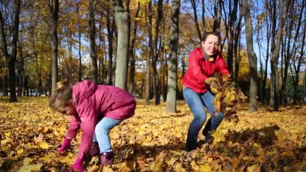 Mother and daughter throw fallen leaves — Stock Video