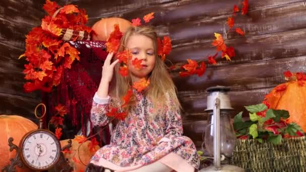 Маленькая девочка сидит в комнате с тыквами — стоковое видео
