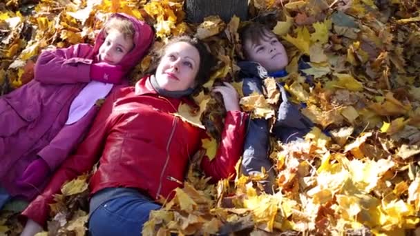 Mother and children lie on fallen leaves — Stock Video